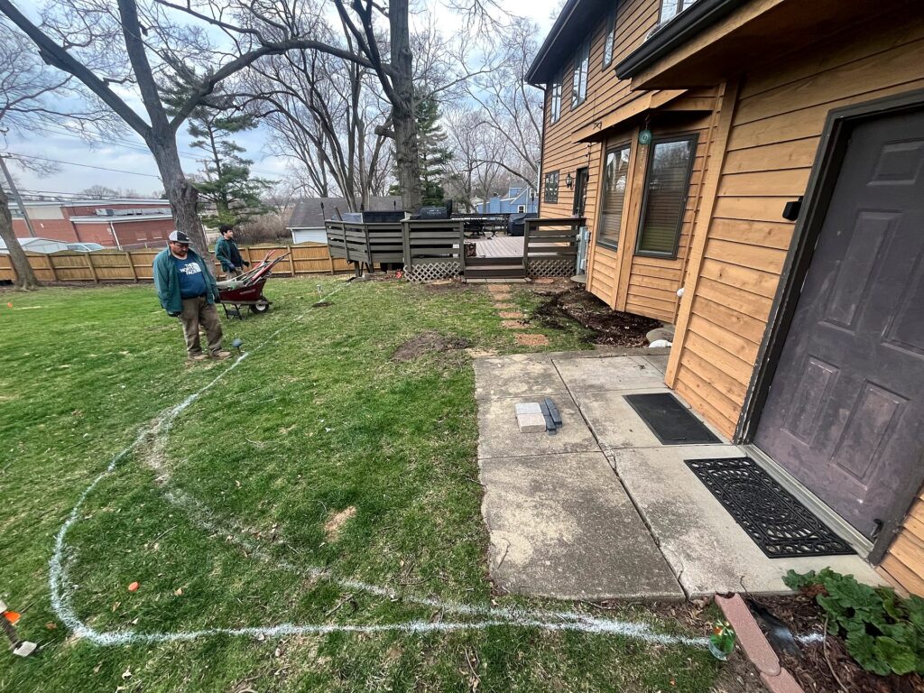 Crew fine-tuning the painted patio curve, with paver samples set out by the back door