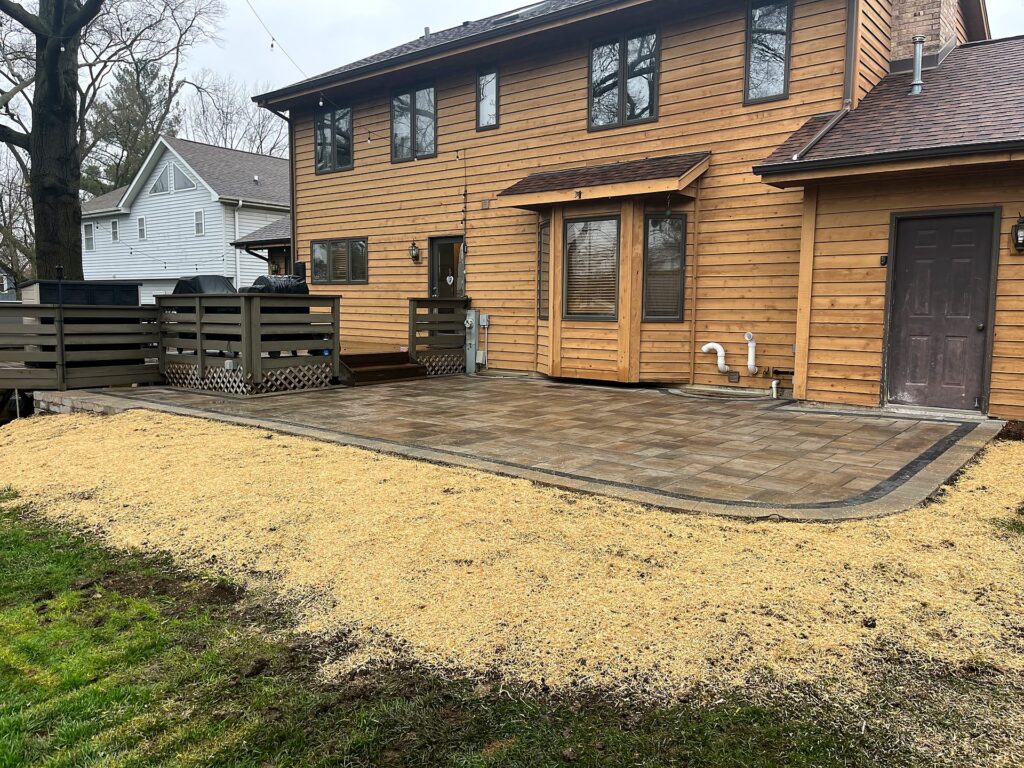 Finished paver patio with a charcoal double border, surrounded by straw over fresh seed