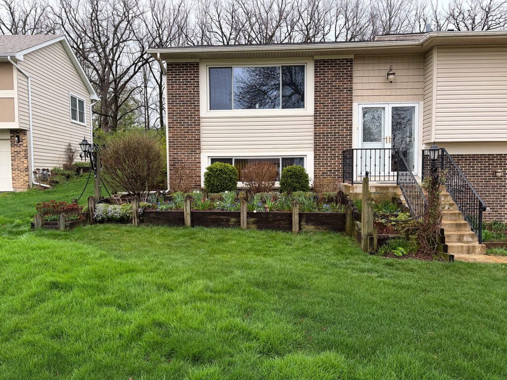 Aging timber retaining wall across the front of the home before replacement